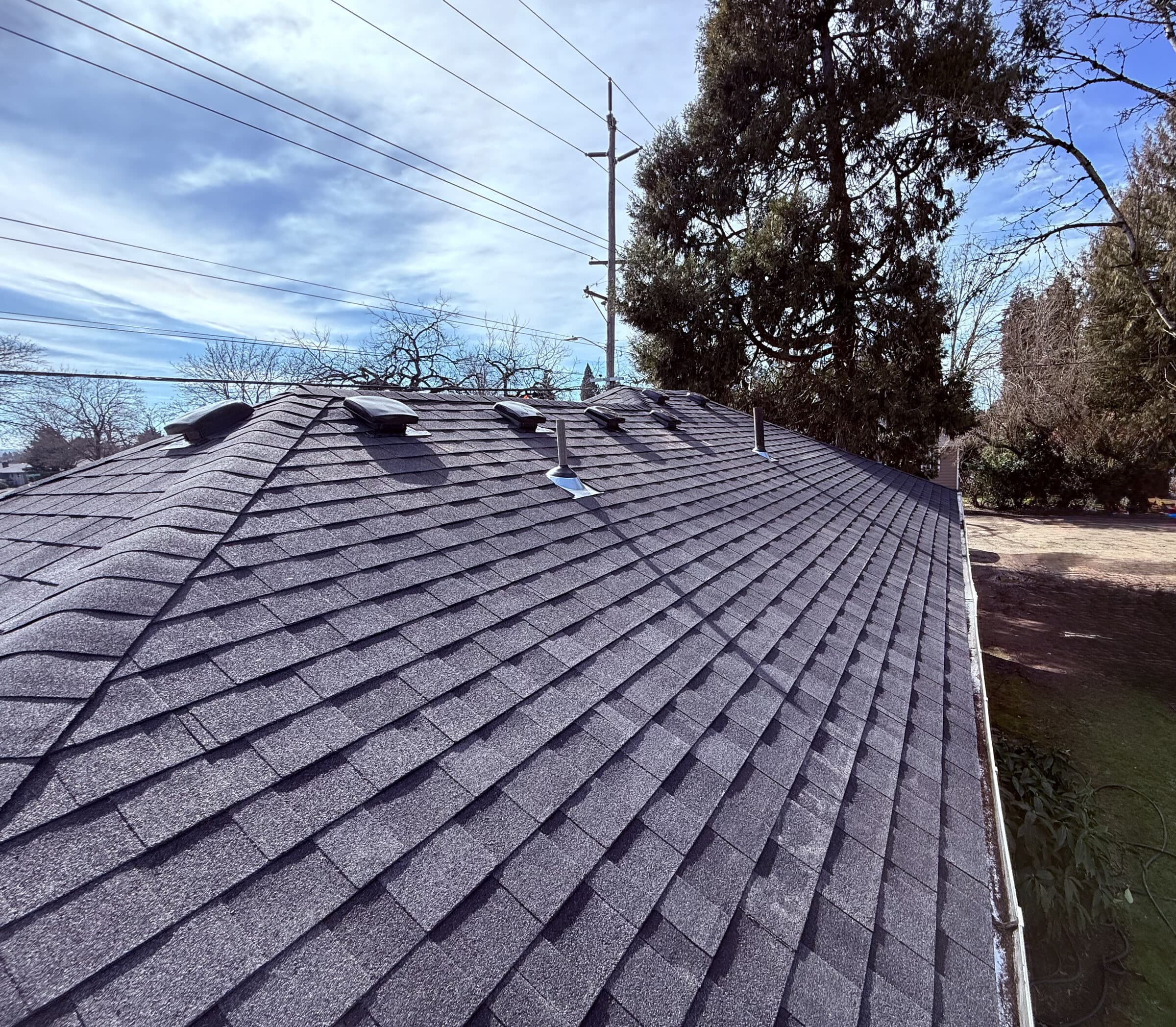 Wide view of new architectural shingle roof with skylights by Denali Builders